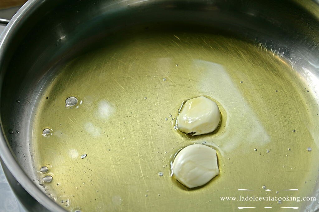 A pan with oil and some cloves of garlic